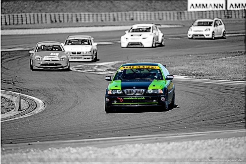 Der grün-schwarze BMW von Sünteltal Motorsport mit der Startnummer 26 vor einer Gruppe von Verfolgern